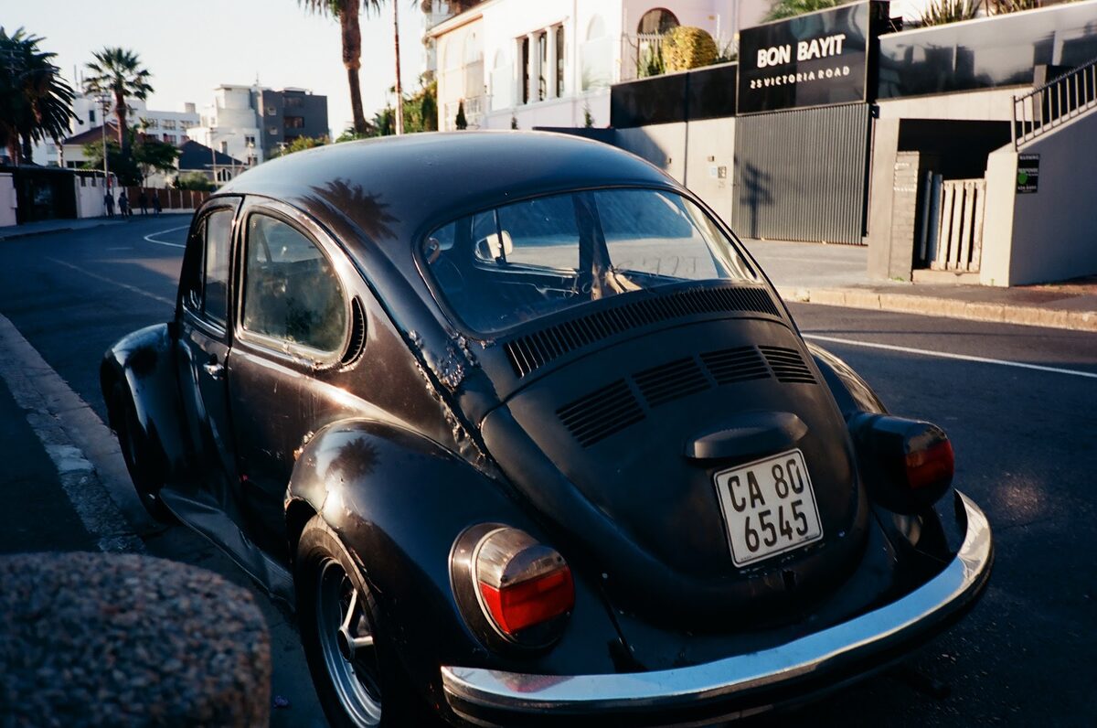 A black Volkswagen Beetle parked on a sunny street