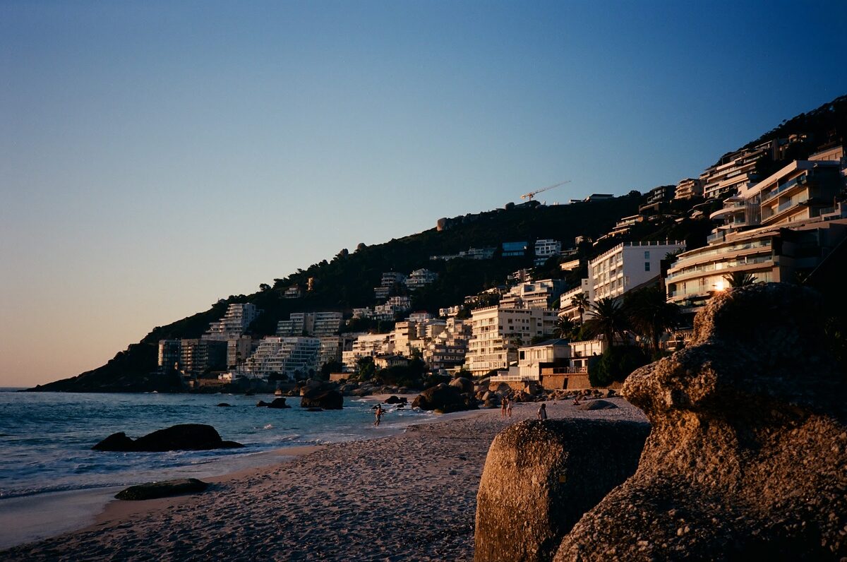 Coastline at dusk, houses stacked up the hillside above a small beach